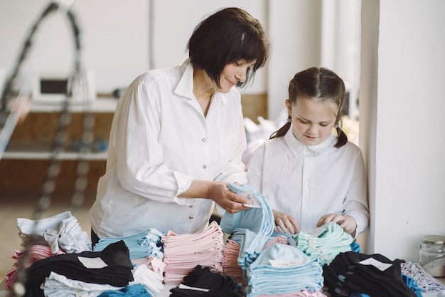 Grandmother with little granddaughter measure the fabric for sewing