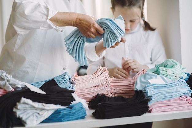 Grandmother with little granddaughter measure the fabric for sewing