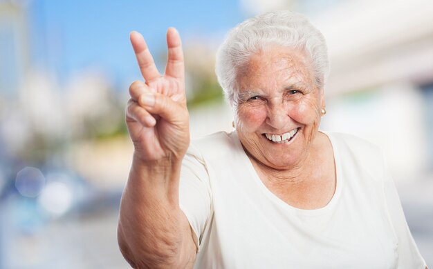 Бабушка с двумя пальцами поднял и улыбается