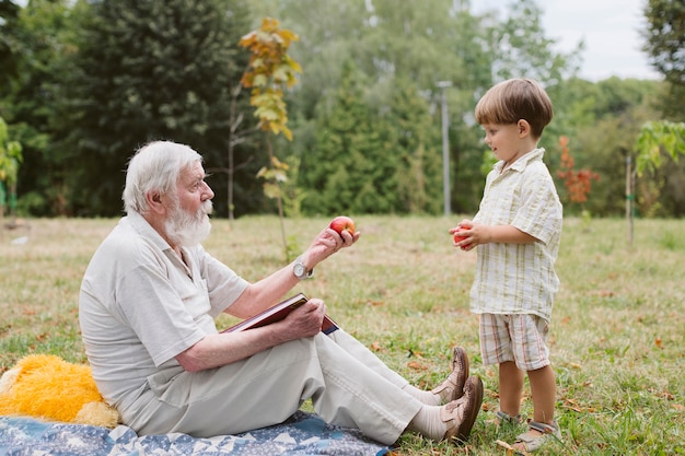Дедушка дает яблоко внуку