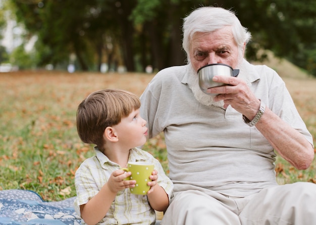 Grandpa and grandson in park drinking tea