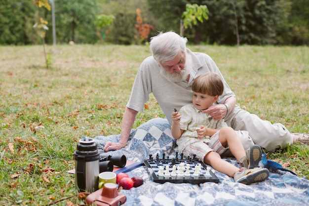 Grandpa hugging grandson and playing chess