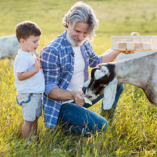 Free photo grandpa and little boy with goat