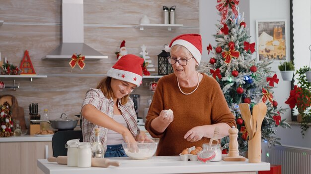 조부모는 손자가 요리 주방에서 집에서 만든 전통 쿠키 반죽을 준비하는 것을 돕습니다.