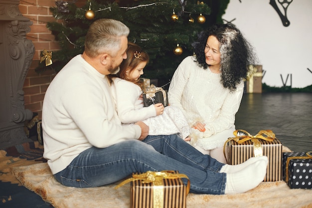 Бабушка и дедушка сидят с внучкой. Встречаем Рождество в уютном доме.