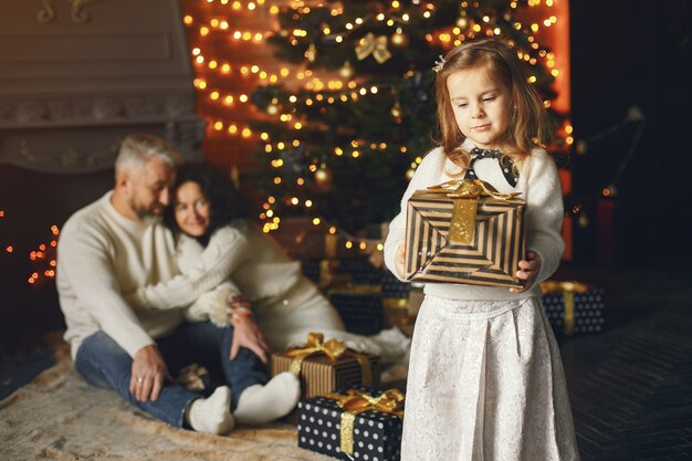 Grandparents sitting with their granddaughter. Celebrating Christmas in a cozy house.