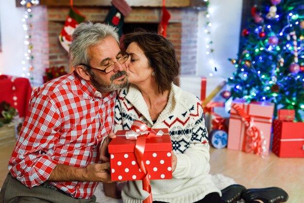 Grandparents together with gift box in their living room