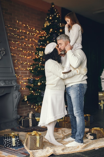 Grandparents with their granddaughter. Celebrating Christmas in a cozy house.