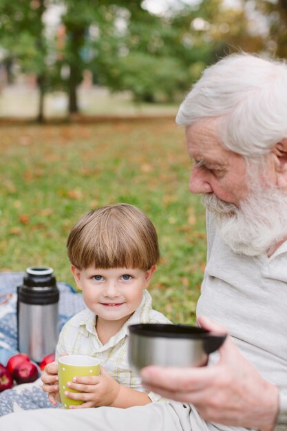 Grandson with grandpa in park drinking tea