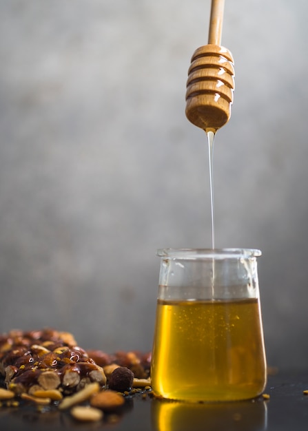 Foto gratuita barretta di muesli con miele che gocciola dalla caraffa di miele in vaso