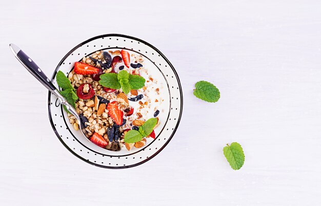 Free photo granola, strawberries, cherry, honeysuckle berry, nuts and yogurt in a bowl