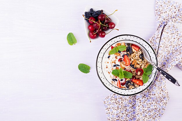 Granola, strawberries, cherry, honeysuckle berry, nuts and yogurt in a bowl