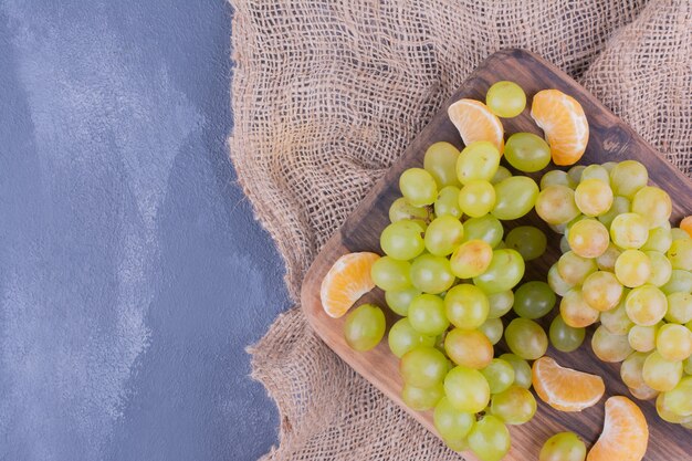 Grape bunches on a wooden board on blue surface