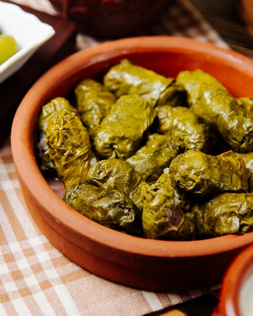 Grape leaves dolma in clay plate minced meat grape leaves spices side view