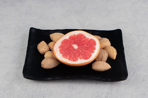 Grapefruit and almonds on the board, on the marble surface