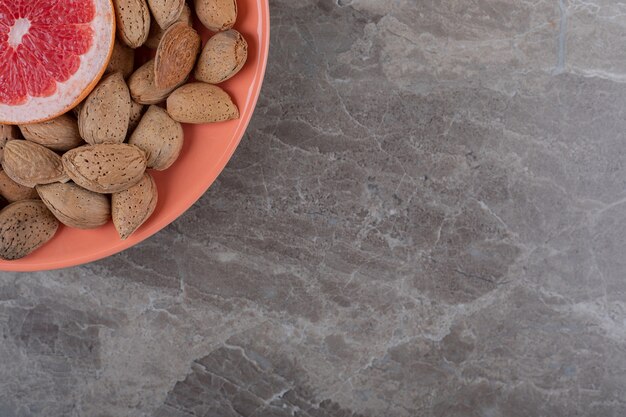 Grapefruit and almonds on the plate on the marble surface