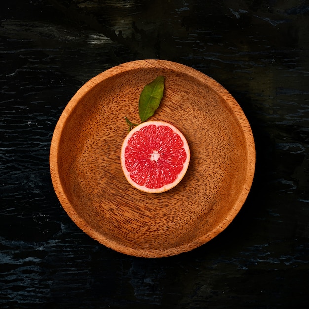 Free photo grapefruit citrus fruit halves on wooden plate