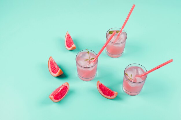 Grapefruit citrus fruit slices and cold juice on mint background