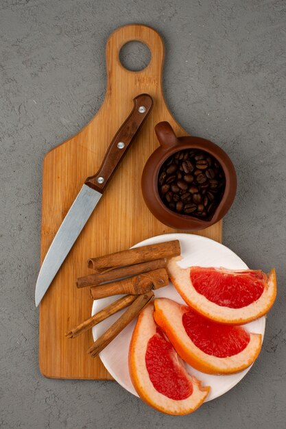 Grapefruit and coffee a top view along with cinnamon on a brown wooden desk and grey