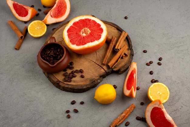 Грейпфрут, лимон, корица, свежие сочные нарезанные фрукты на коричневом деревянном столе и свет