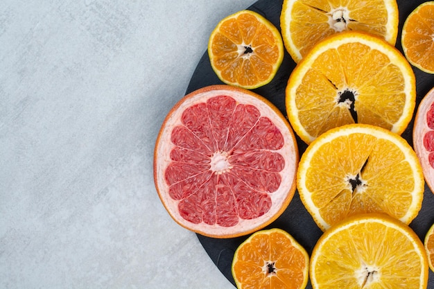 Grapefruit, orange and tangerine slices on black board. High quality photo