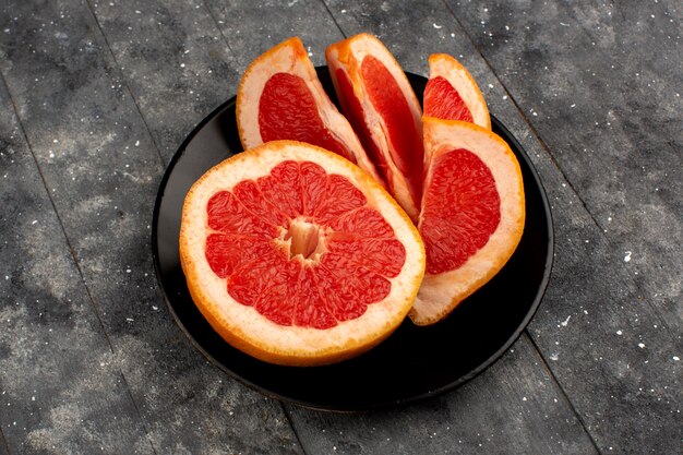 Grapefruit rings sliced fresh juicy inside black plate on the light