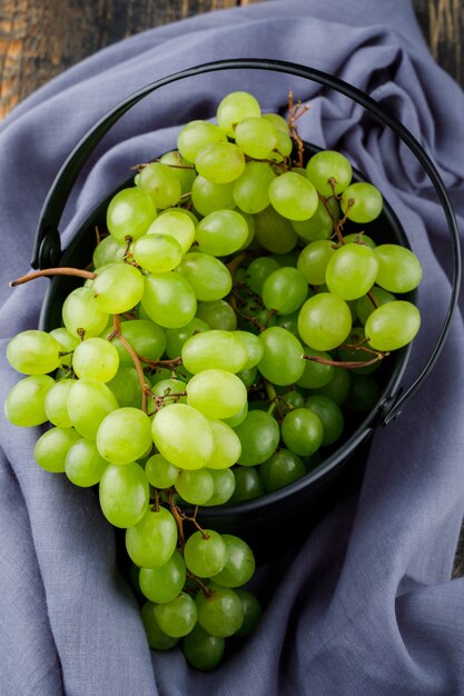 Grapes in a bucket on wooden surface. flat lay.