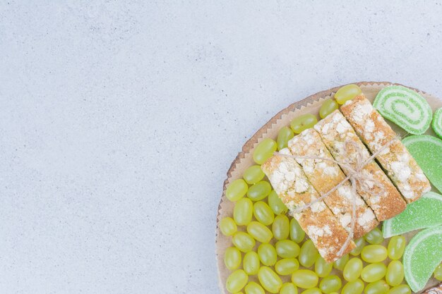 Grapes, cake and marmalades on wooden board. 