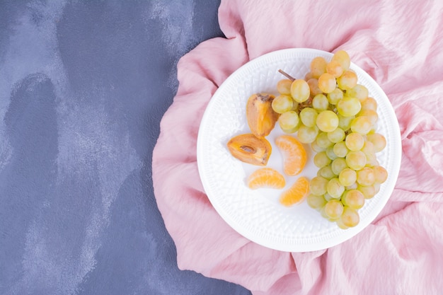 Free photo grapes and date plums in a white plate