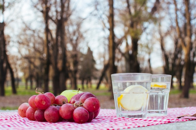 Виноград рядом с бокалами с водой и лимоном