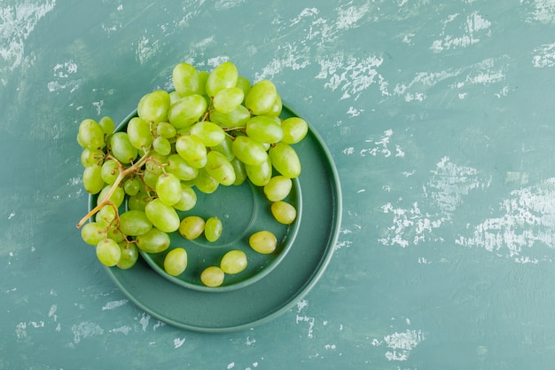 Grapes in saucer and plate flat lay on a plaster background