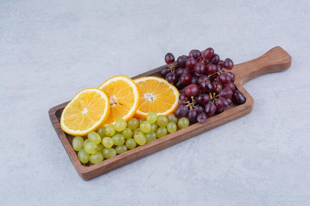 Grapes and slices of orange on wooden board. High quality photo