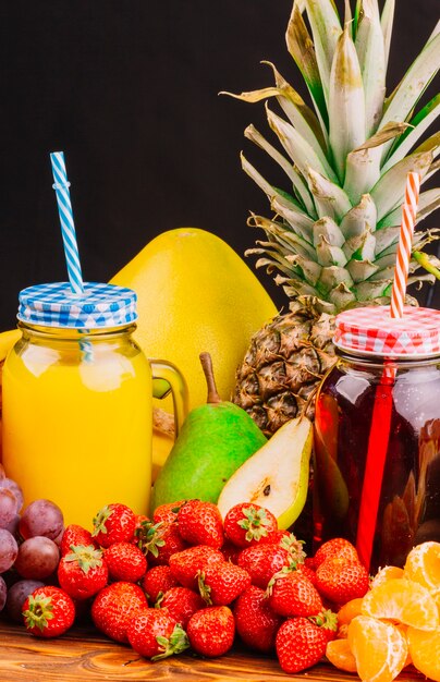 Grapes; strawberries; pears; pineapple and juice bottle against black background