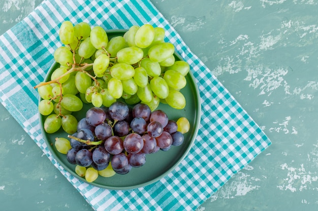 Grapes in a tray on plaster and picnic cloth background. flat lay.
