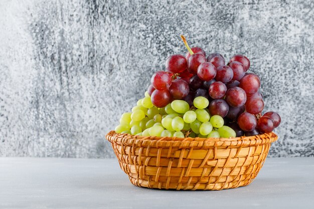 Grapes in a wicker basket on grungy grey and plaster.