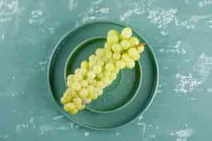 Free photo grapes with plate in a saucer on plaster background, flat lay.