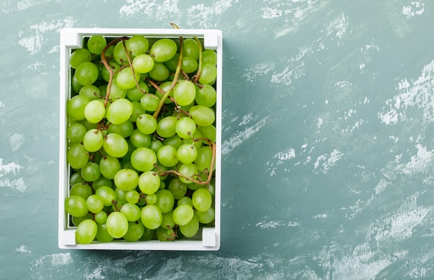 Grapes in a wooden box top view on a grungy plaster background