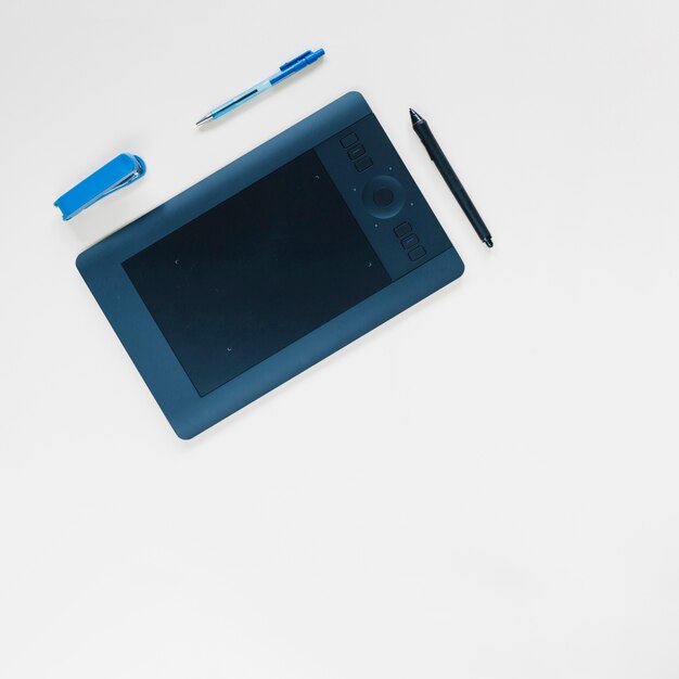 Graphic digital tablet; pen and stapler on white surface