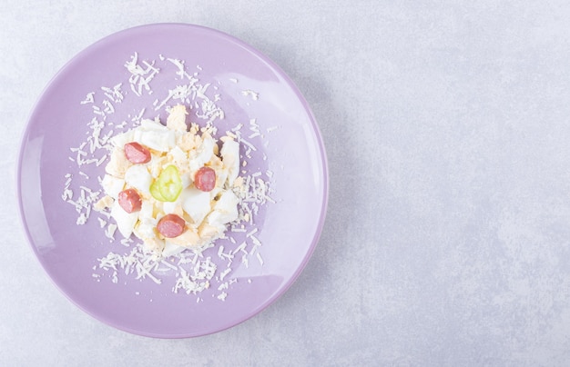 Grated cheese and egg with sausages on purple plate. 