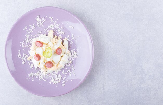 Grated cheese and egg with sausages on purple plate. 