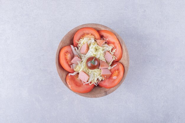 Grated cheese with sausages and tomatoes in wooden bowl. 