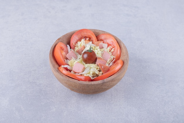 Grated cheese with sausages and tomatoes in wooden bowl. 