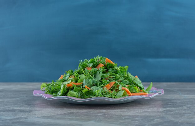 Grated greens on the plate , on the marble table. 