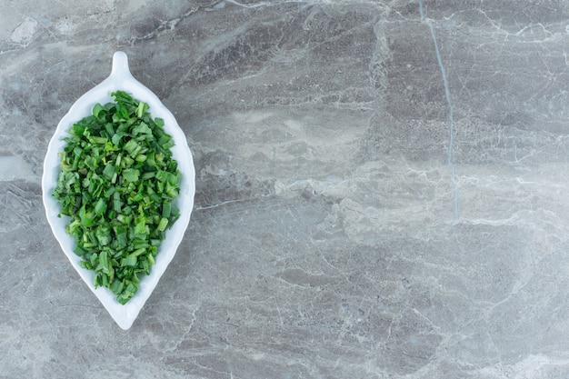 Grated greens on the platter , on the marble table. 