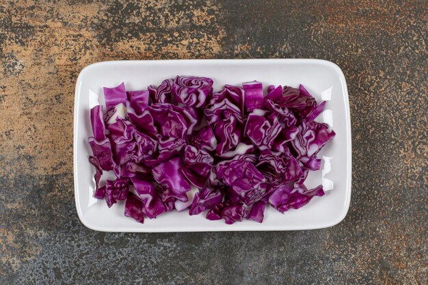 Grated red cabbage in the bowl, on the marble surface