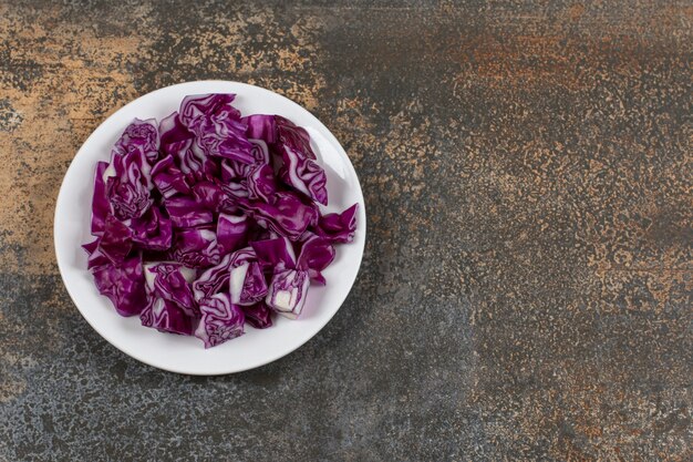 Grated red cabbage in the bowl, on the marble surface