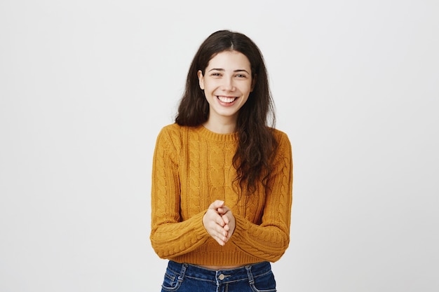 Grateful smiling girl clasp hands together and looking happy