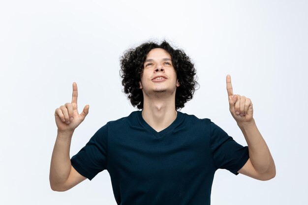 Grateful young handsome man looking up pointing fingers up isolated on white background