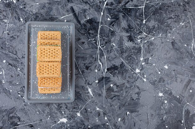 A gray board of sweet waffles placed on a marble .