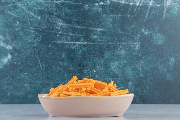 Free photo gray bowl of crispy crackers placed on stone background.